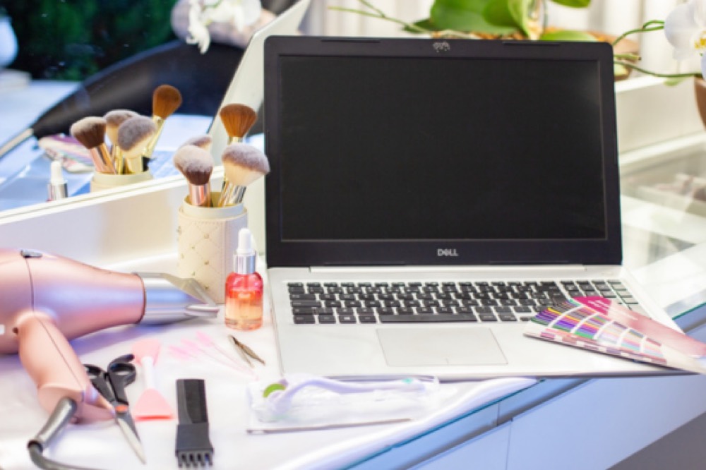 Bancada de trabalho de uma profissional da beleza com pincéis e notebook